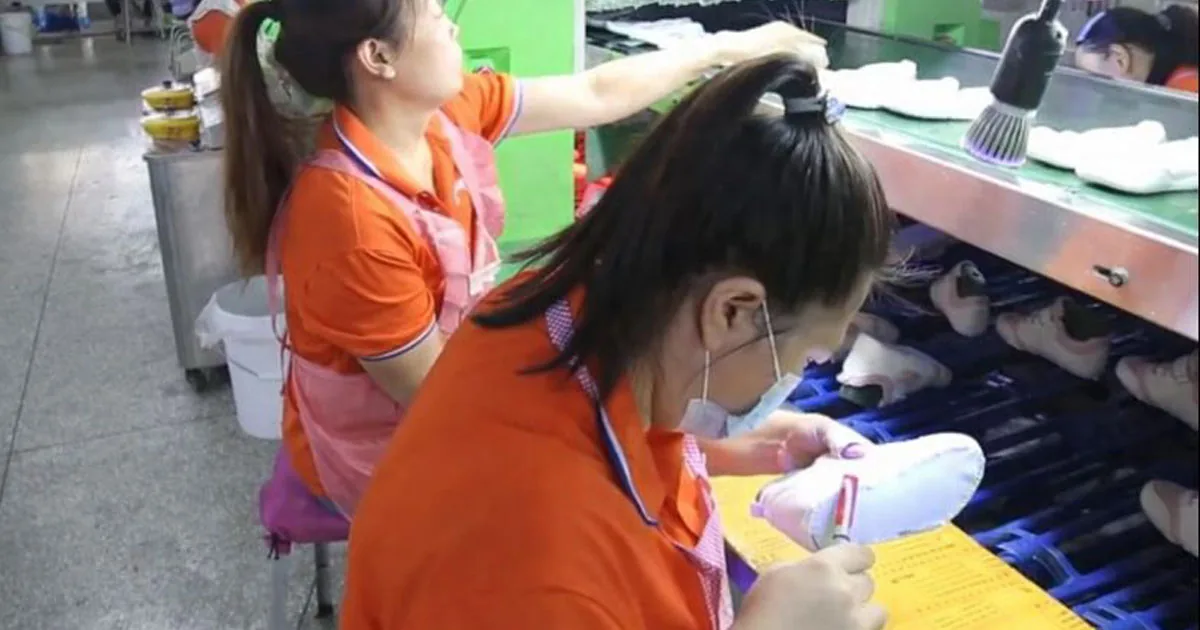 Footwear quality inspectors checking finished shoe samples at a production line